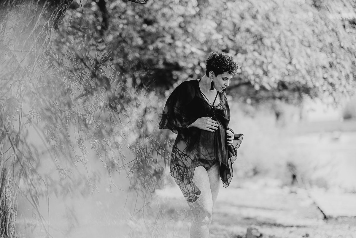 Babybauch Shooting, schwangere Frau in schwarzem Negligee in der Natuar, Schwarzweißbild