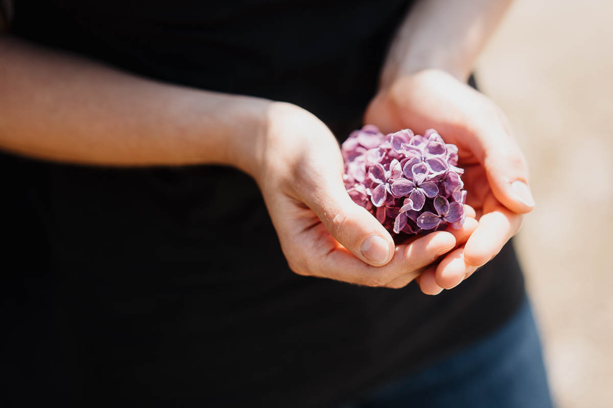 authentische paarfotos annelie brux fotografie
Frau hält eine Fliederblüte in der Hand.
