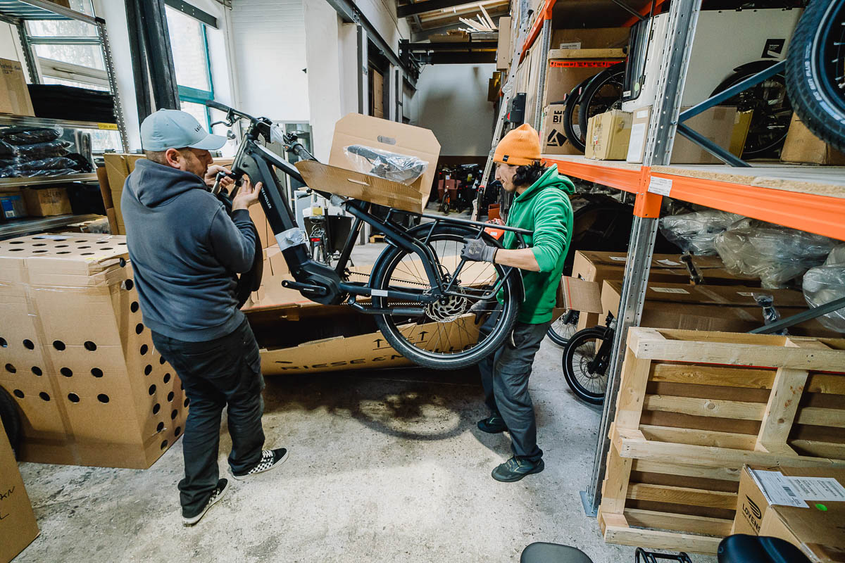 Businessfotografie Unternehmen Beratung und Lager - ein Elektrofahrrad wird im Lager aus einem Karton gehoben
