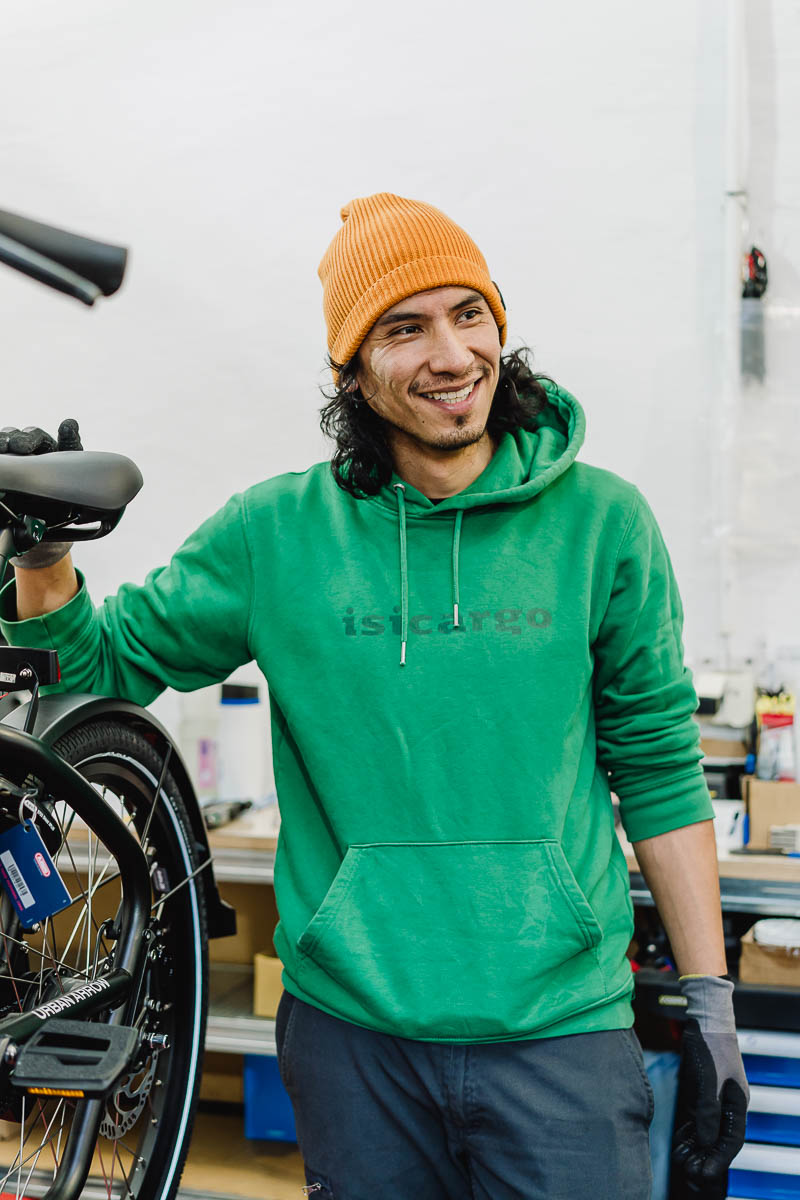 Mitarbeiterportraits in Dienstkleidung mit dem Firmenlogo in der Fahrradwerkstatt