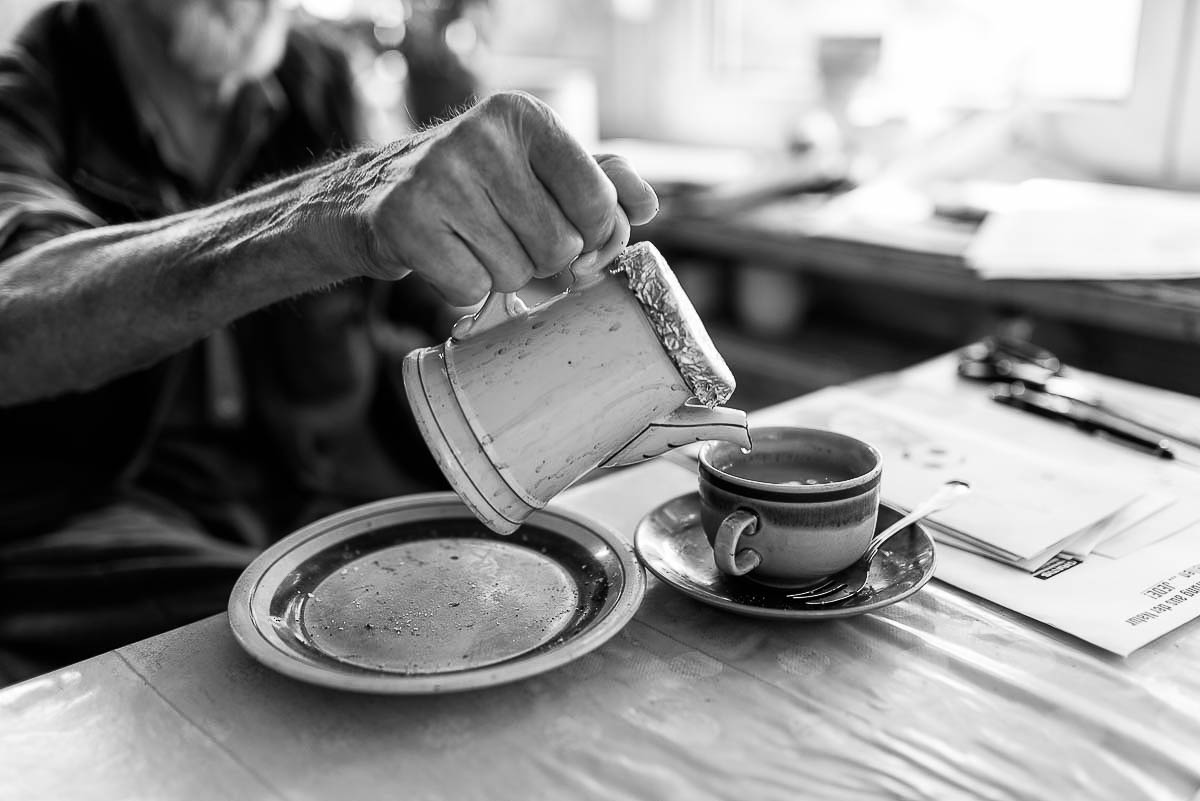 Abschiedsfotografie mit Details eines alten Mannes, der sich einen Kaffee eingießt. Letzte Erinnerungen.