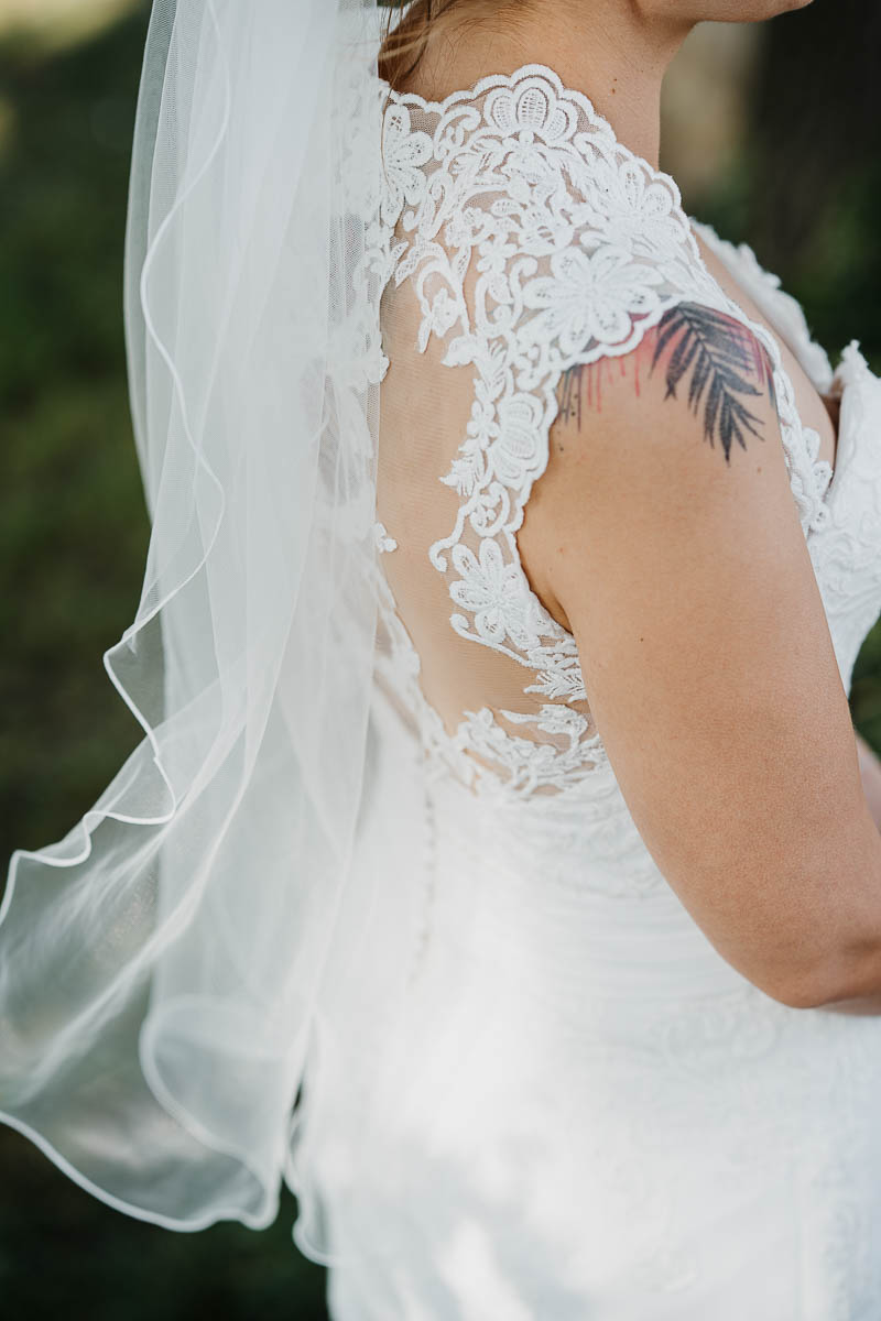 Detailaufnahme der feinen Spitze am Brautkleid und des Tattoos der Braut.