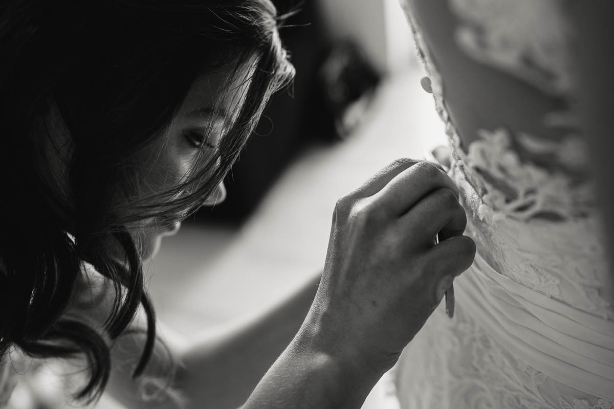 Braut bekommt Hilfe von ihrer Trauzeugin beim Anziehen des Brautkleides während einer Hochzeitsreportage in Radebeul.