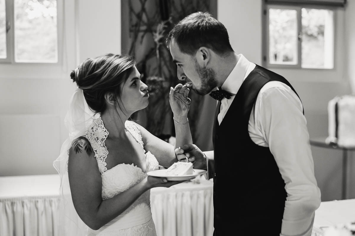 Braut und Bräutigam füttern sich gegenseitig mit Hochzeitstorte - eine schöne Tradition.